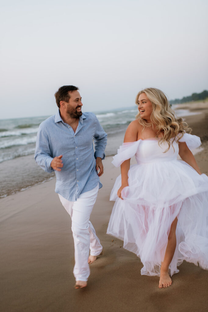 Couple running along the shoreline for their New Buffalo Beach engagement photos in MI.