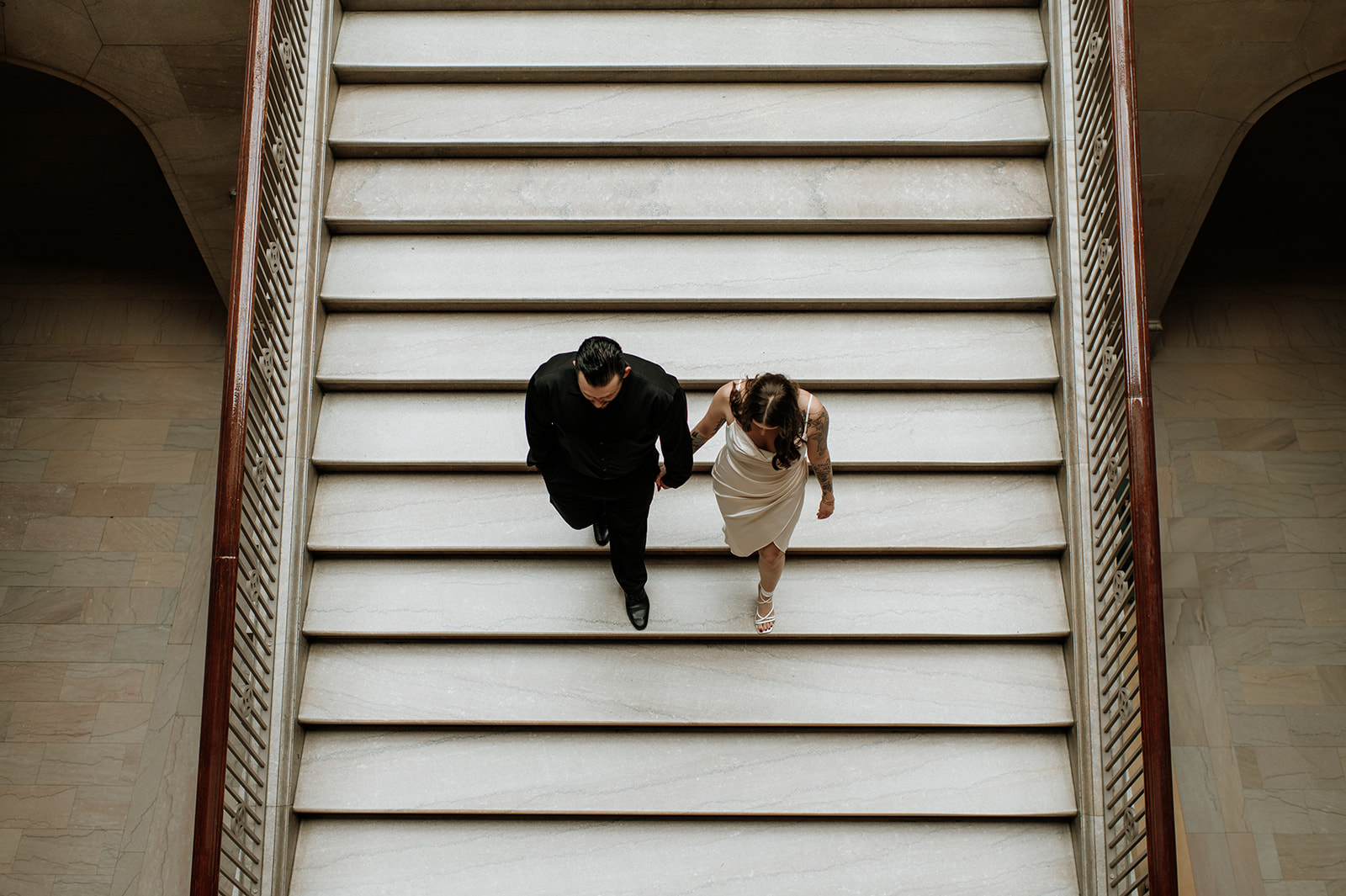 Couple walking down a set of stairs for their museum engagement photos in Indiana.