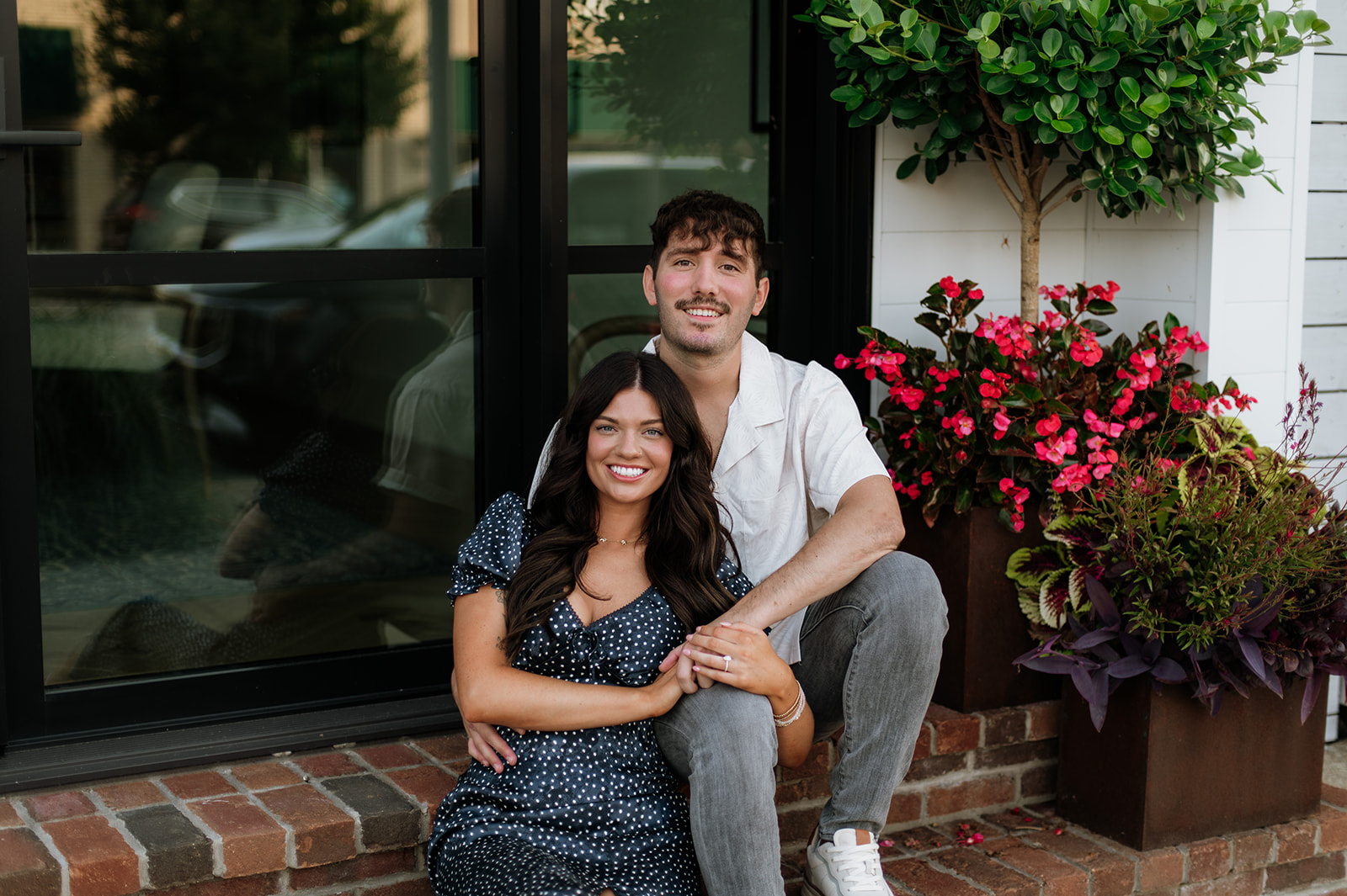 Couple sitting together in front of a building for their engagement session.
