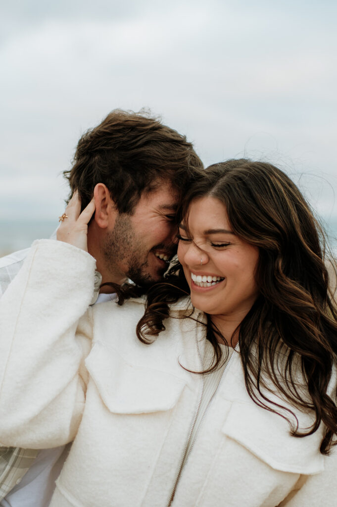 Couple smiling and laughing during their winter engagement photos.