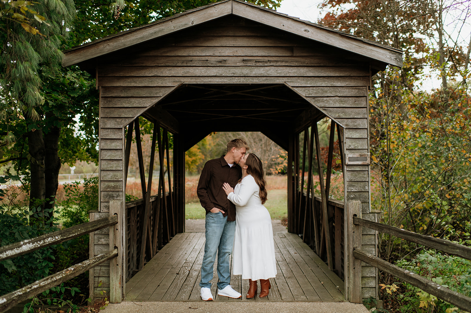 Couple kissing under a wooden structure for their Northern Indiana engagement photos.