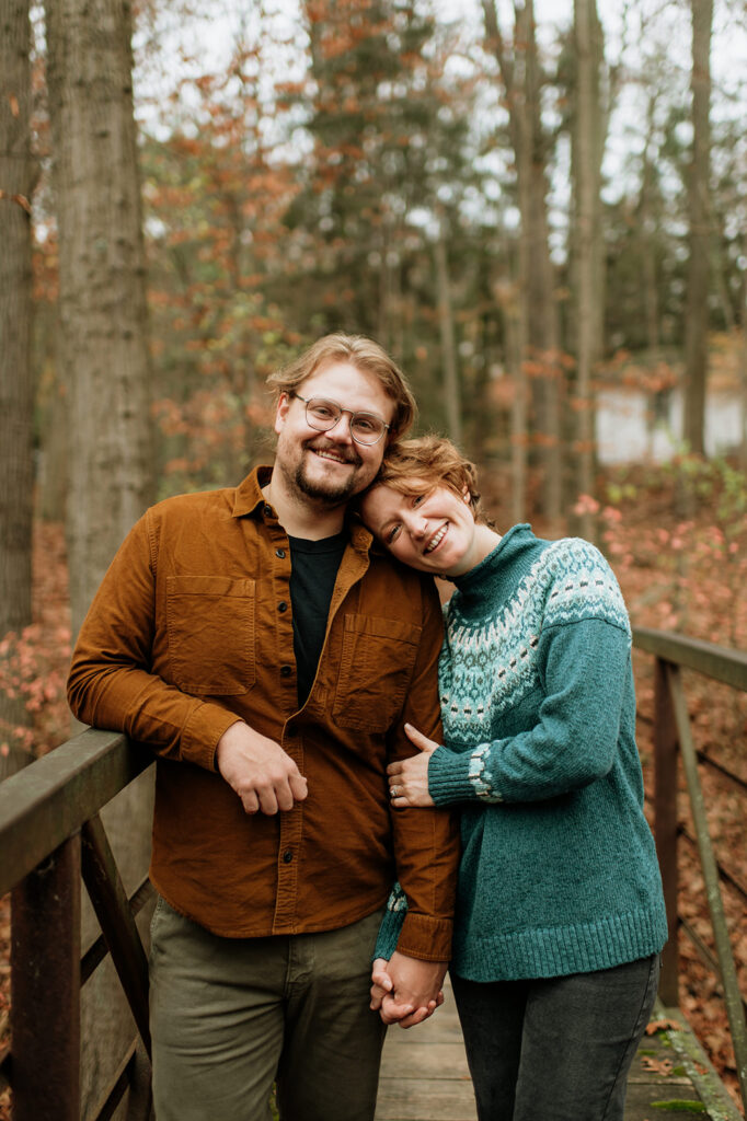 Couple posing during the fall for their cozy engagement photos near Lake Michigan.