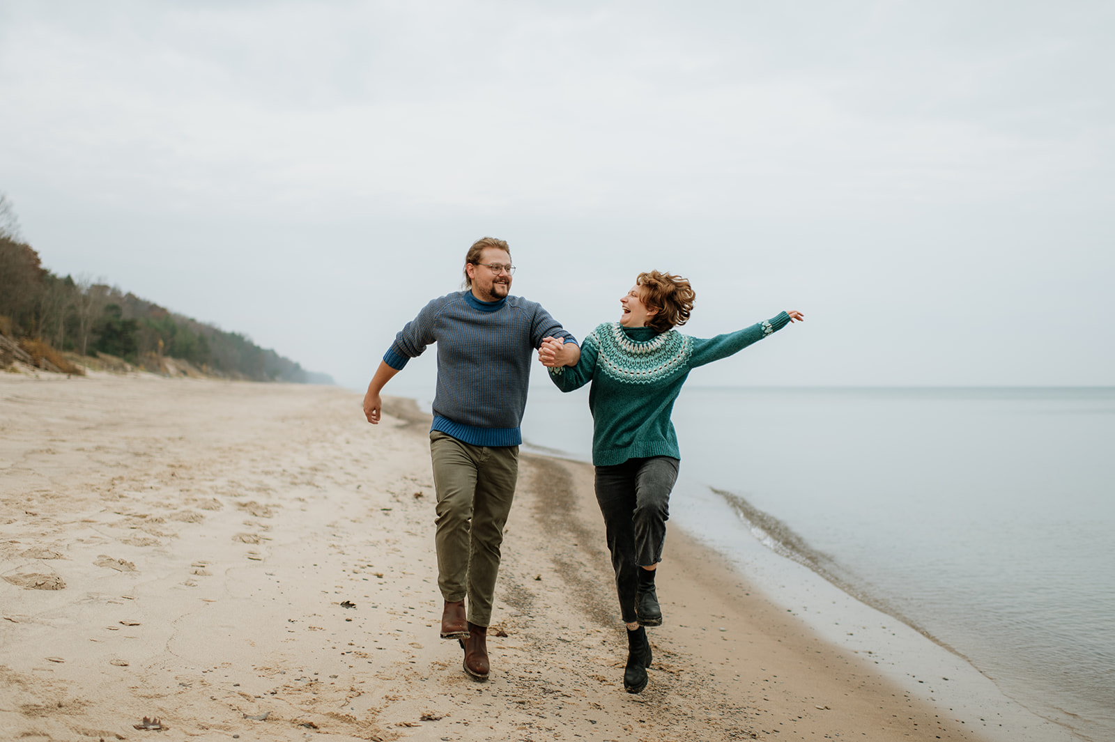 Couple laughing and skipping along the shoreline of Lake Michigan.