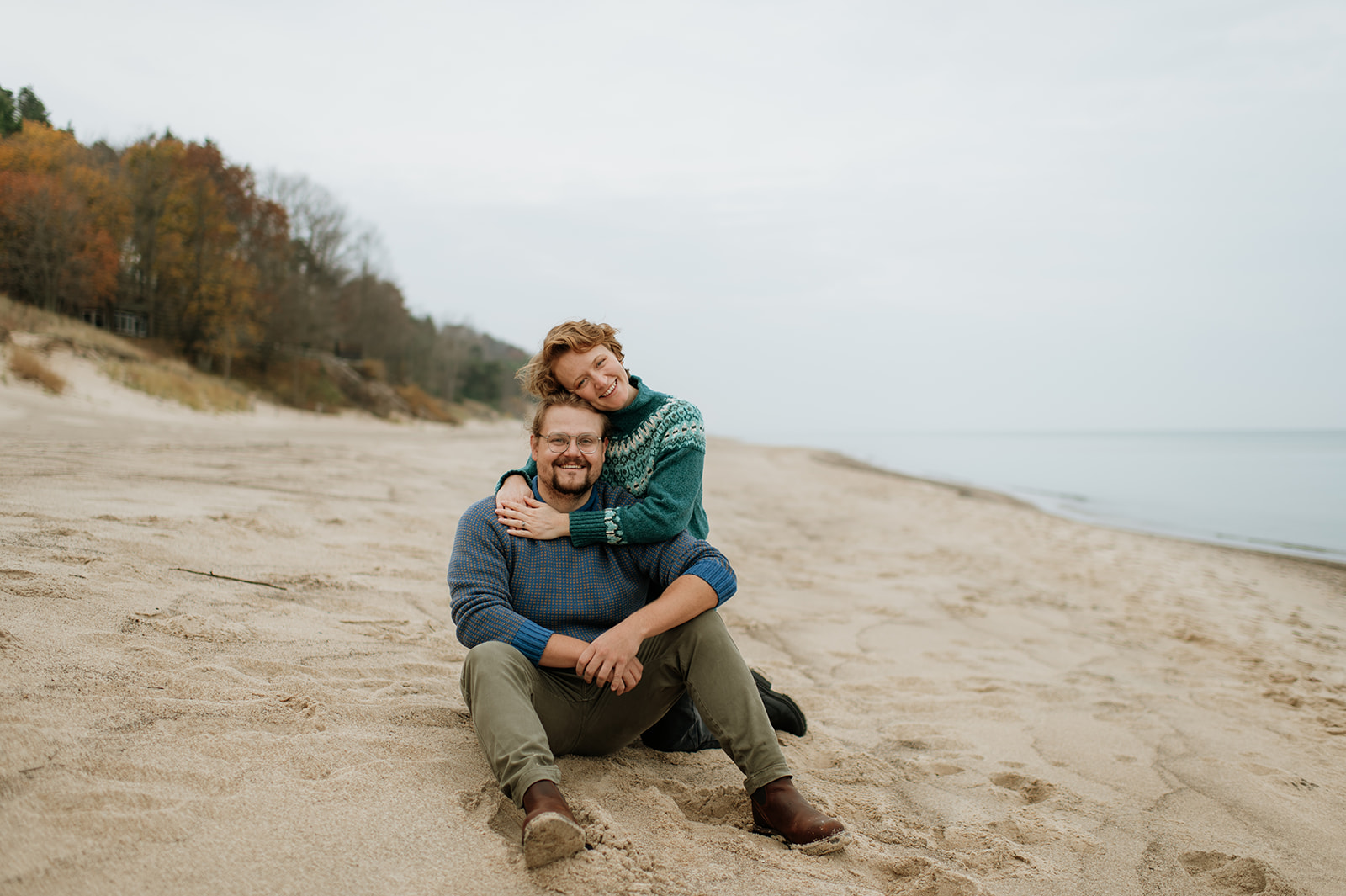 Couple posing on the beach near Lake Michigan for their fall engagement photos.