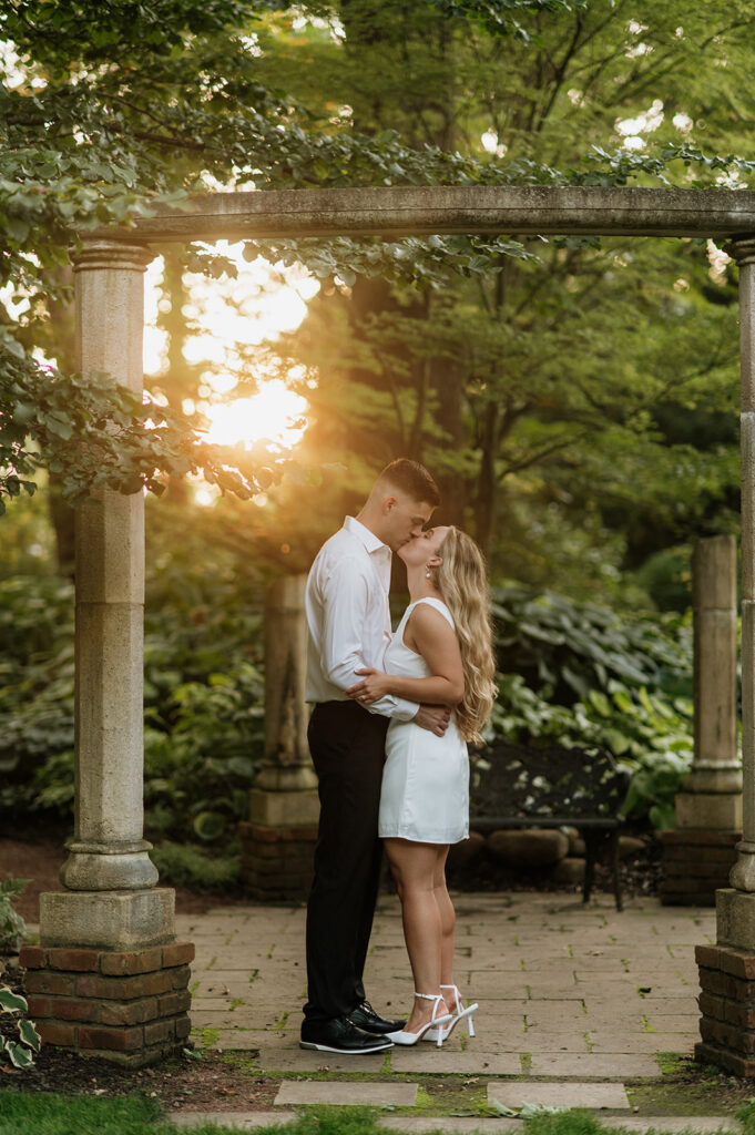 Couple kissing during golden hour in a garden setting.