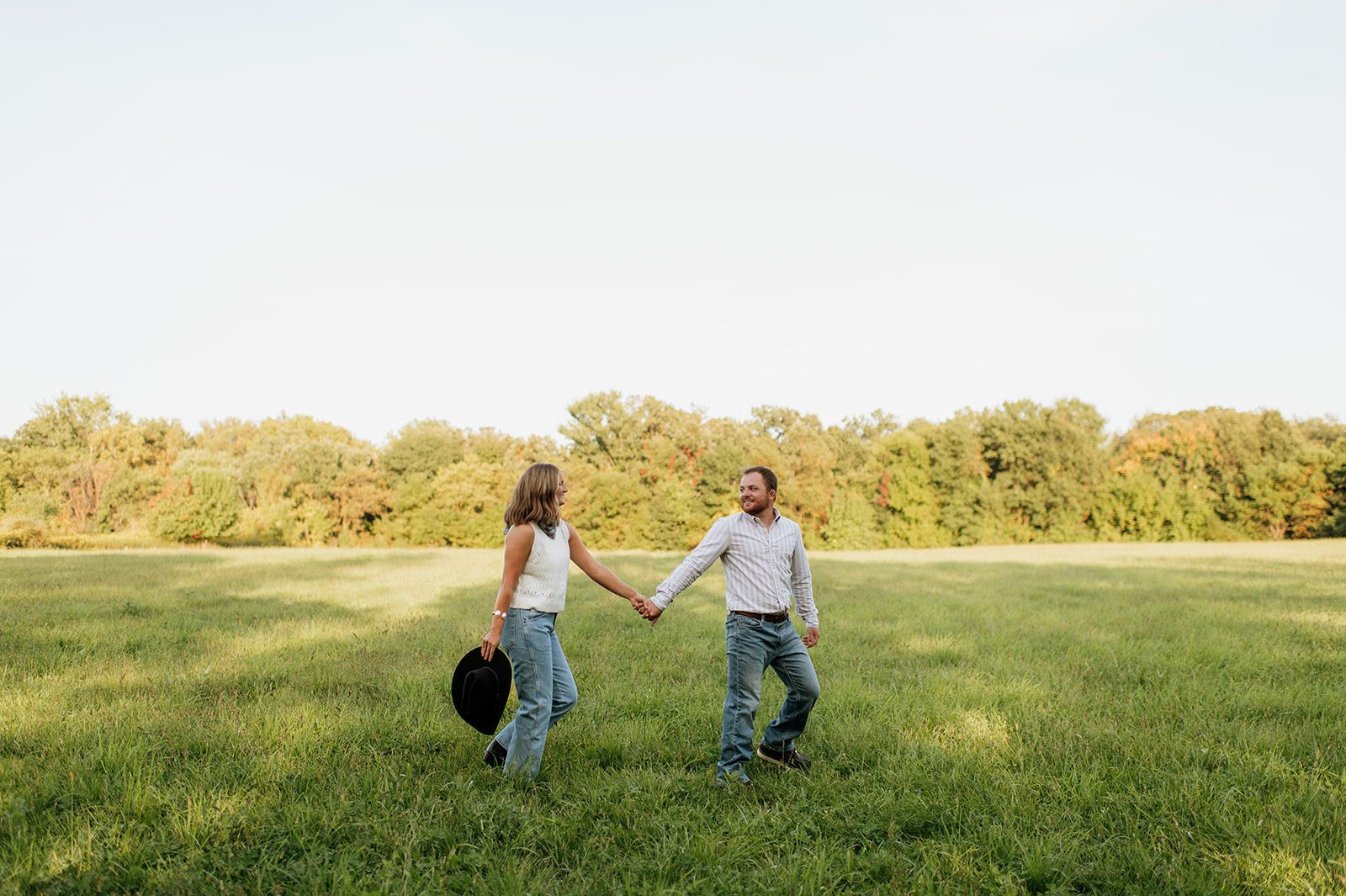 Couple holding hands and walking across an open field.