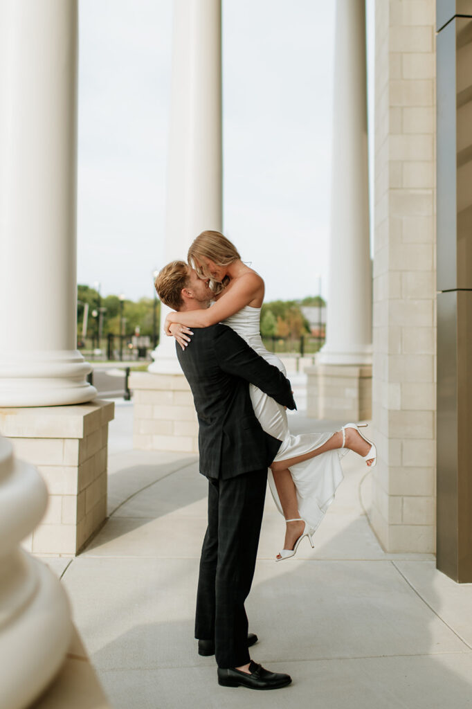 Man lifting up his fiancé during their Goshen, Indiana engagement photos.
