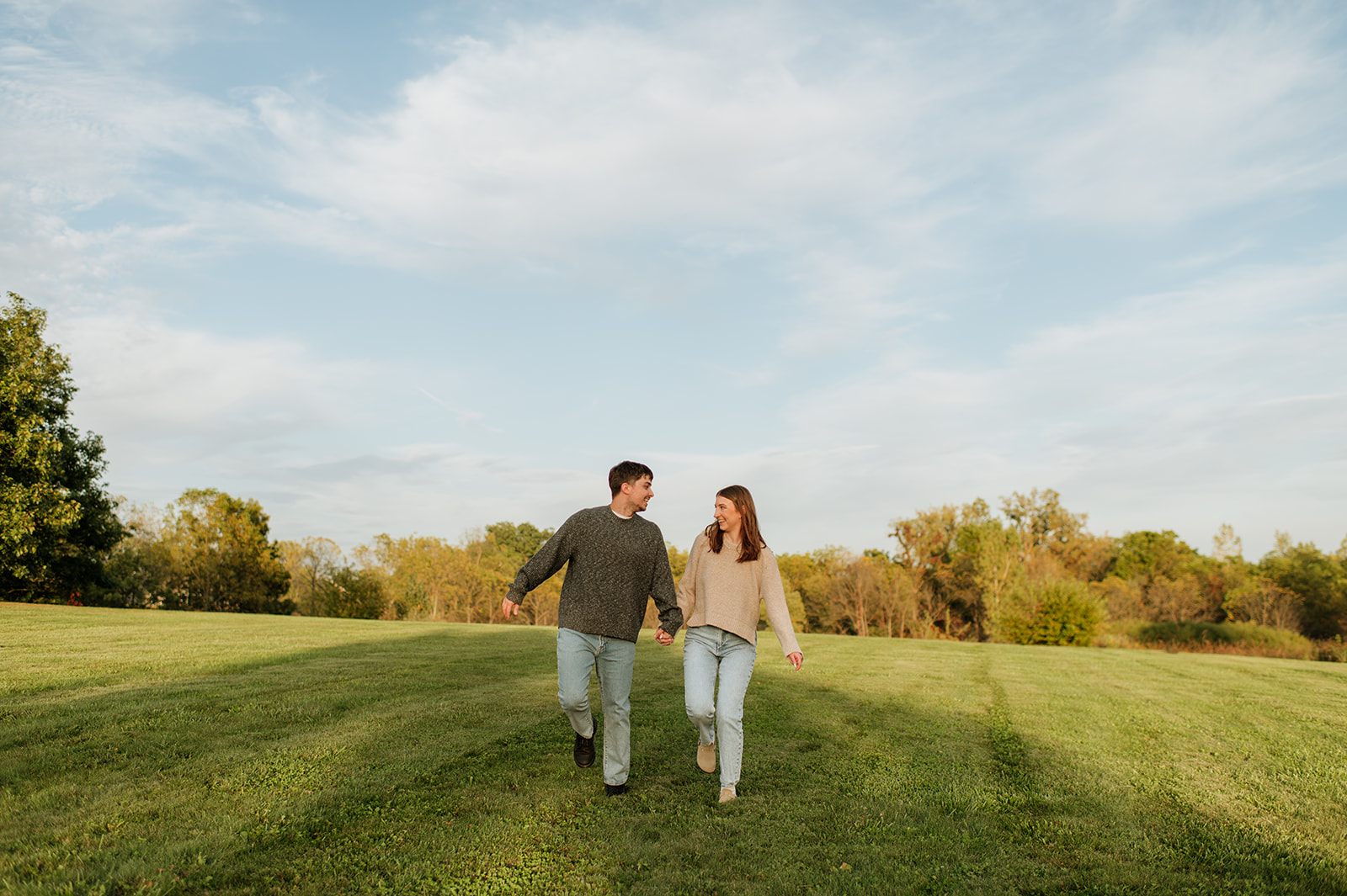 Couple walking in an open grassy area for their Indiana engagement photos.