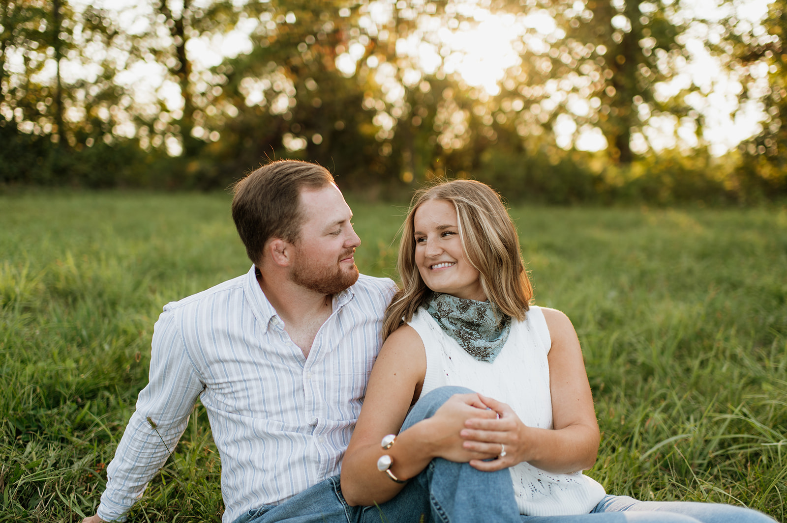 Couple sitting in the grass during golden hour.