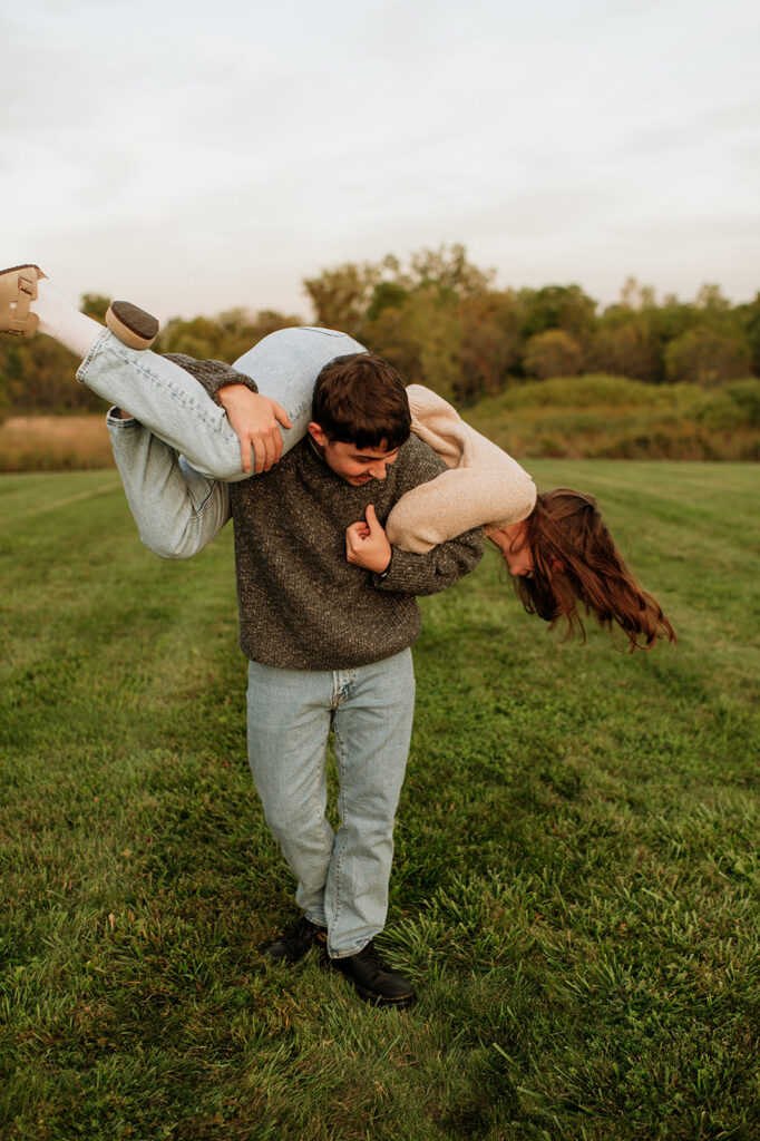 Man lifting his partner over his shoulder during their playful engagement photos.