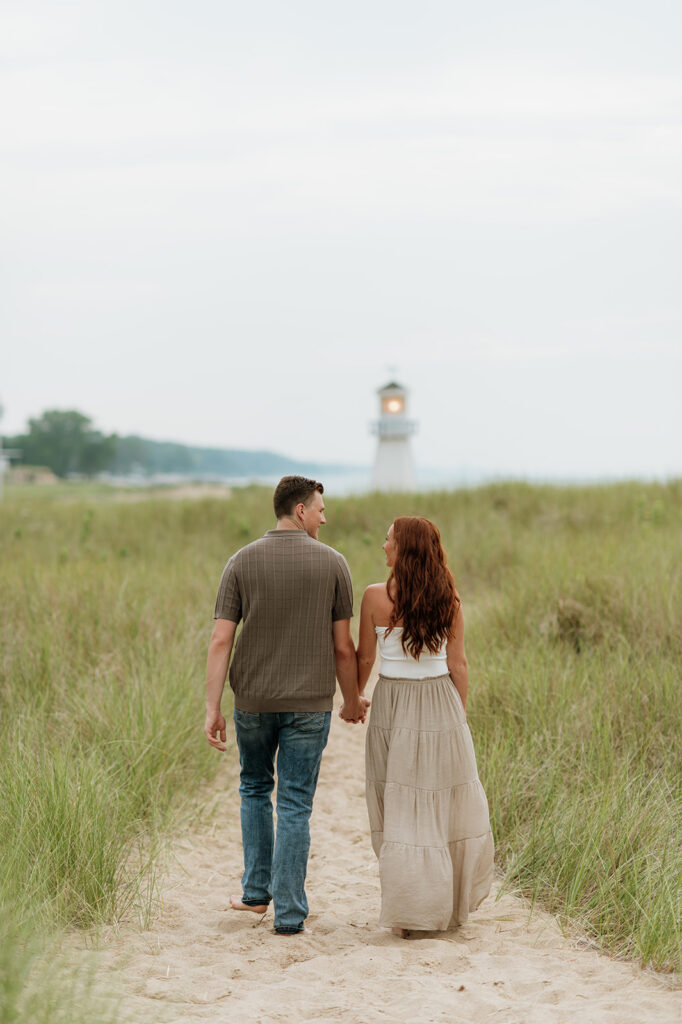 Couple walking along a beach path for their New Buffalo engagement photos.