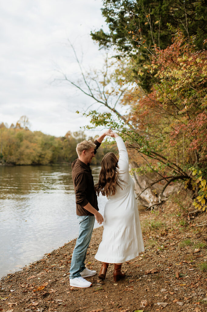 Man twirling his fiancé during their outdoor fall engagement session.