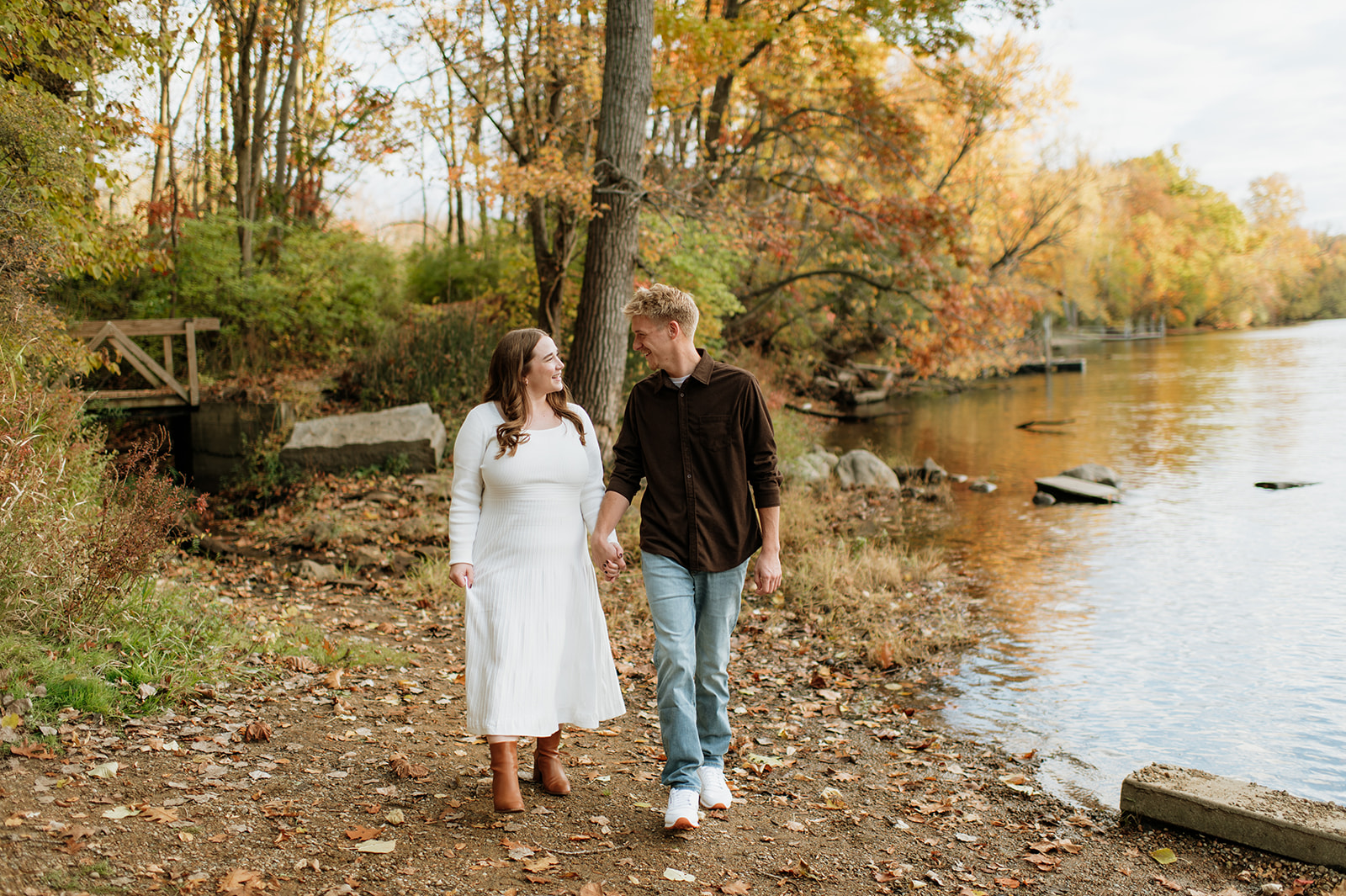 Couple holding hands and walking near water during their South Bend engagement photos at St. Patrick’s County Park.