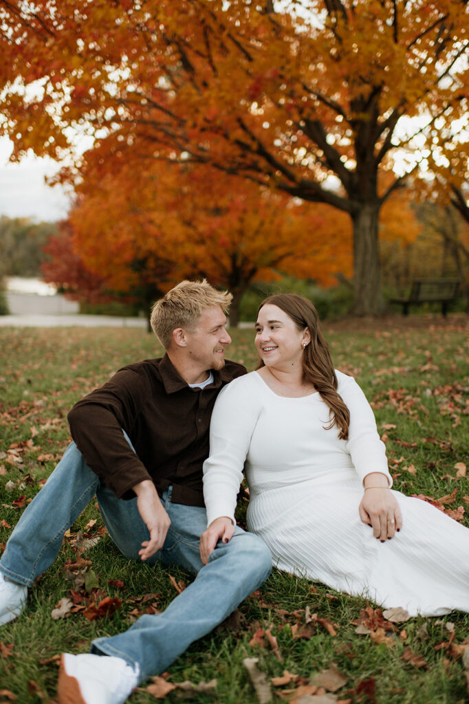 Couple posing together in the grass during their fall engagement photos in South Bend, Indiana.