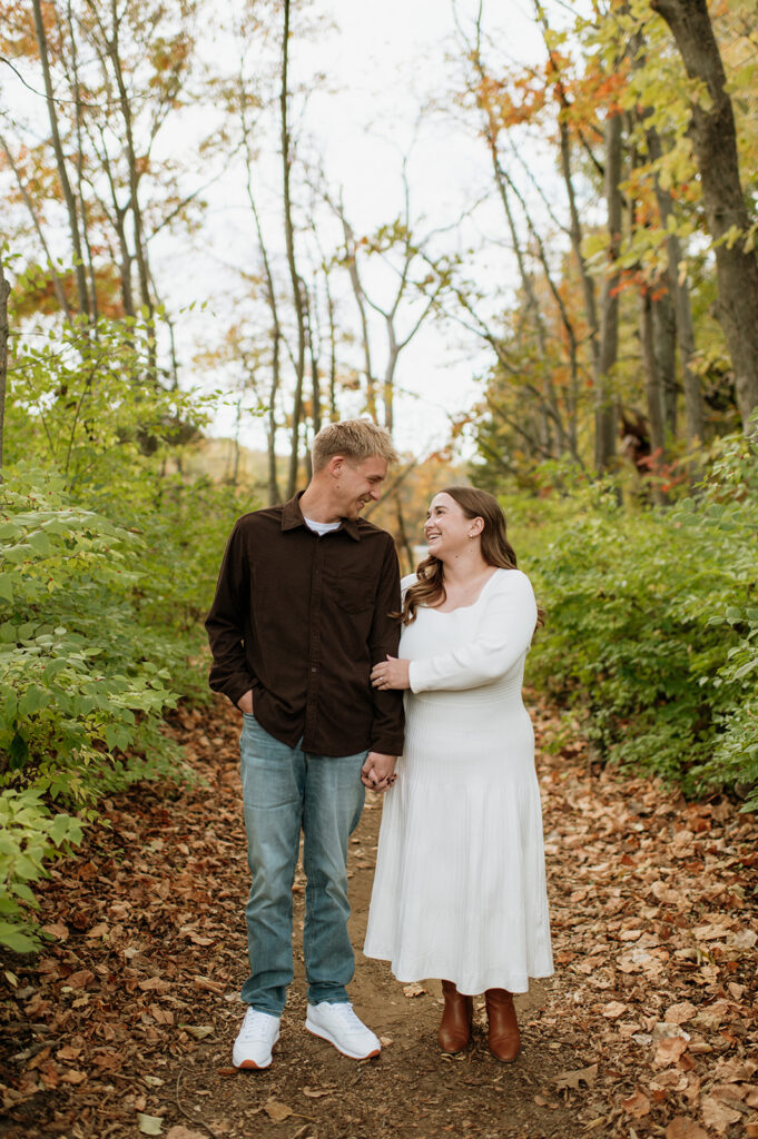 Couple walking down dirty pathways during their outdoor fall South Bend engagement photos at St. Patrick’s County Park.