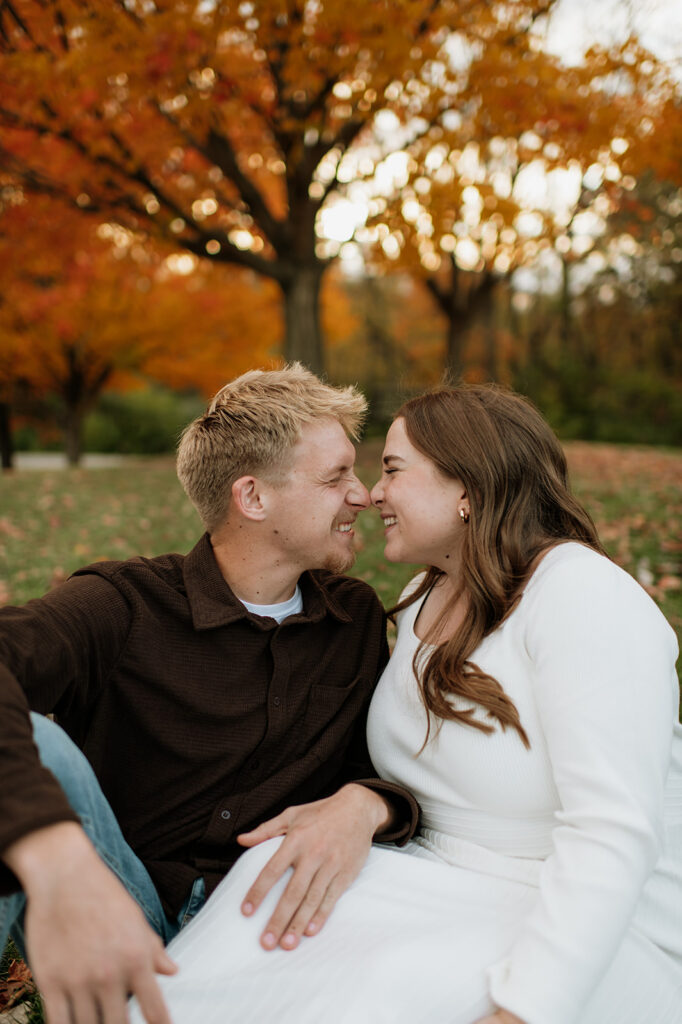 Couple laughing and scrunching their noses together during their fall session.