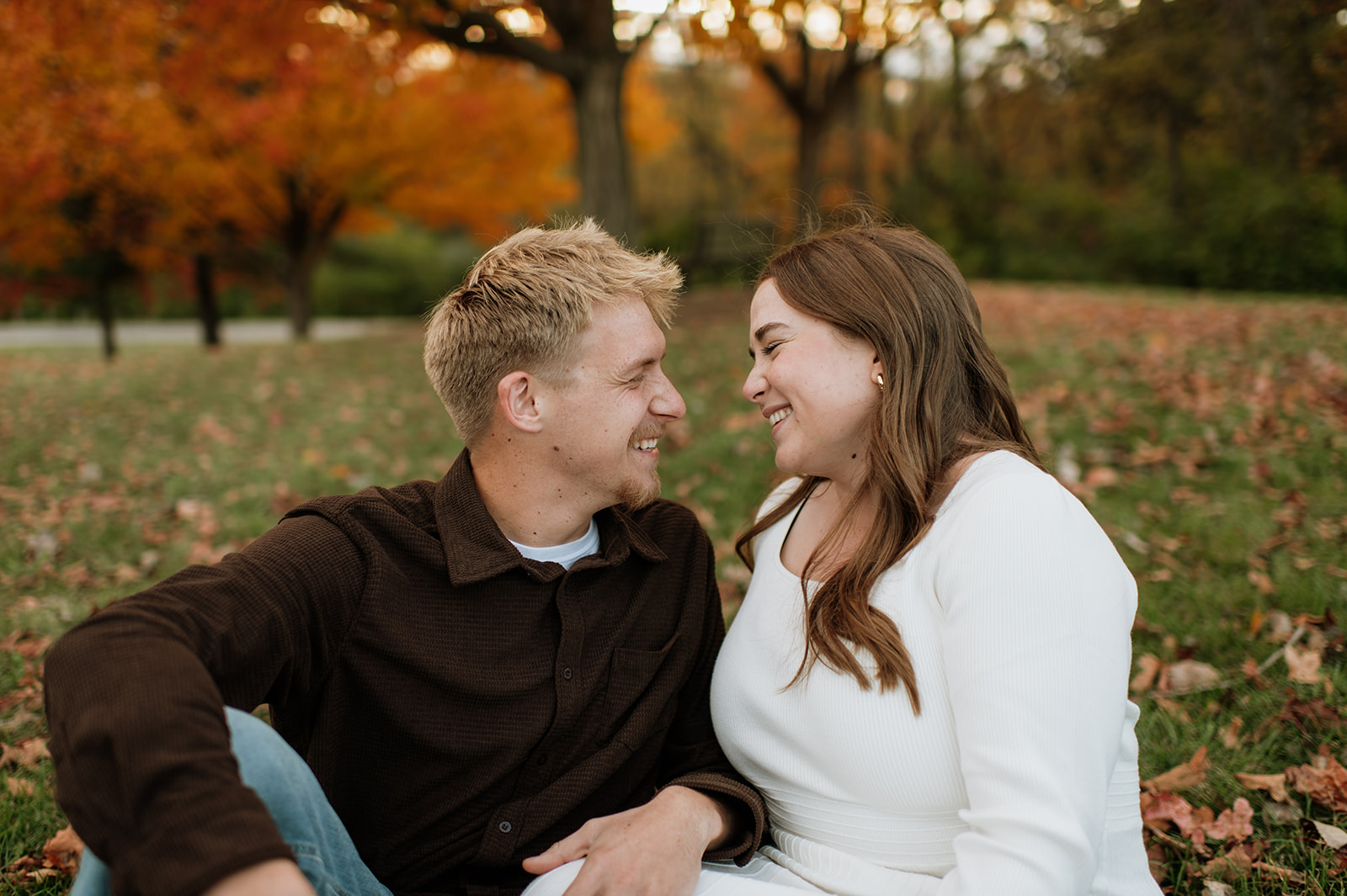 Couple laughing in the grass during their fall South Bend engagement photos.