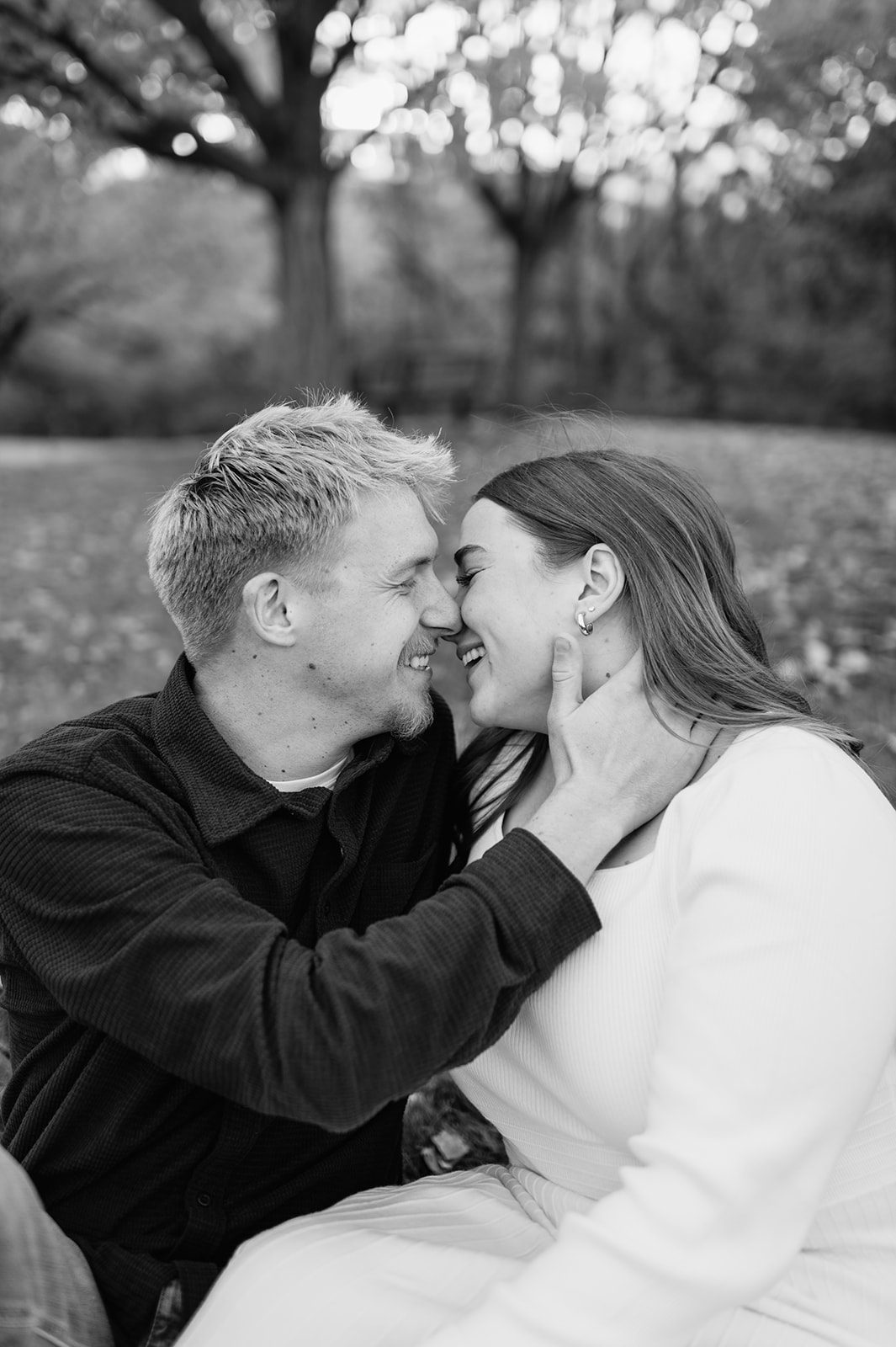 Black and white photo of a couple laughing and going in for a kiss.