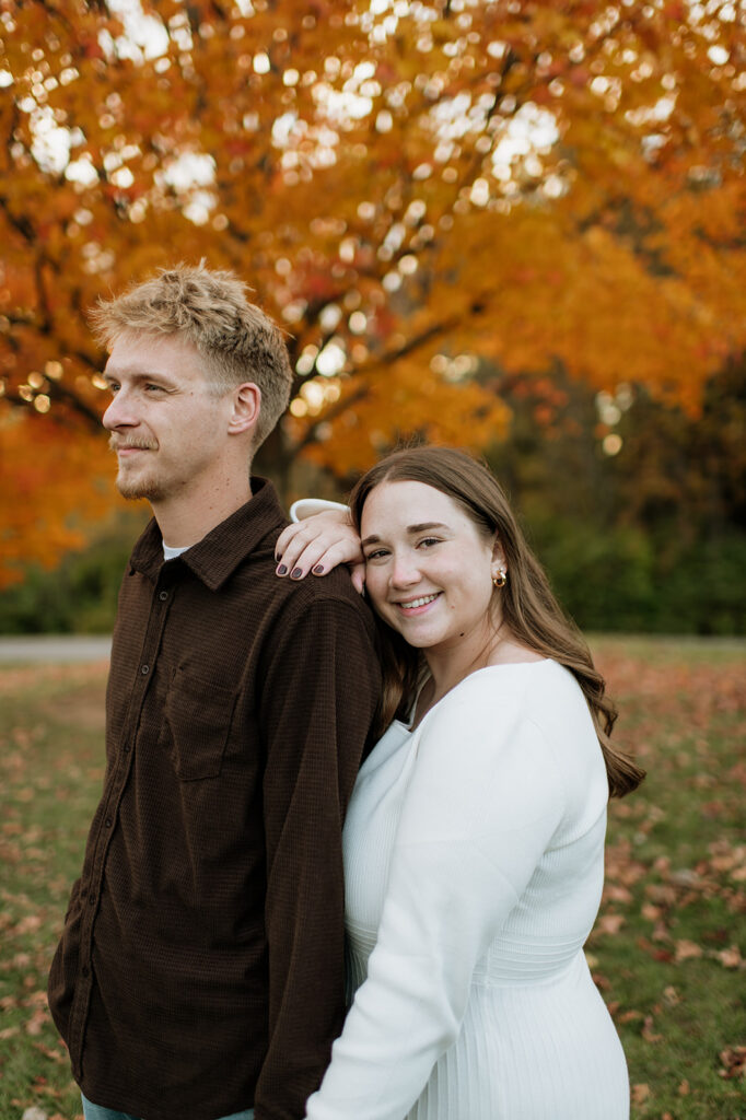 Couple posing side by side for their outdoor fall engagement photos.