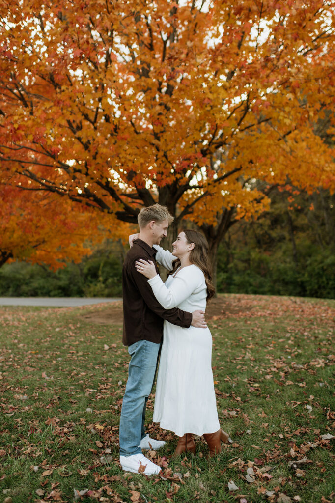 Couple holding one another during their fall engagement session.