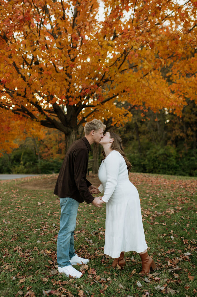 Couple kissing in front of fall foliage during their South Bend engagement photos at St. Patrick’s County Park.