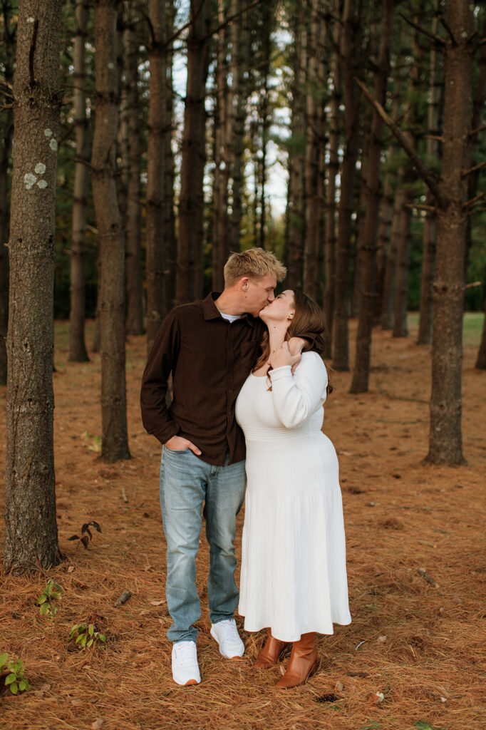 Couple kissing amongst tall trees for their South Bend engagement photos at St. Patrick’s County Park.