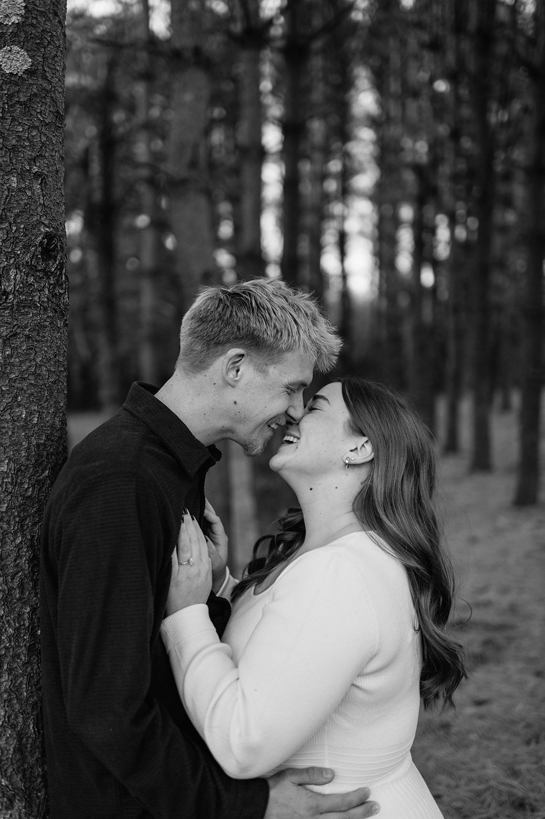 Black and white photo of a couple posing against a tall tree during their South Bend engagement photos at St. Patrick’s County Park.