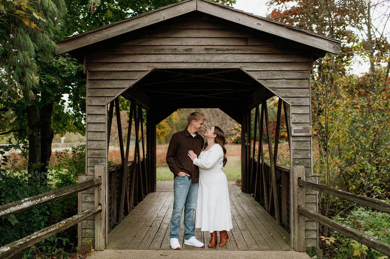 Couple smiling at one another as they pose on a covered bridge for their South Bend engagement photos at St. Patrick’s County Park.