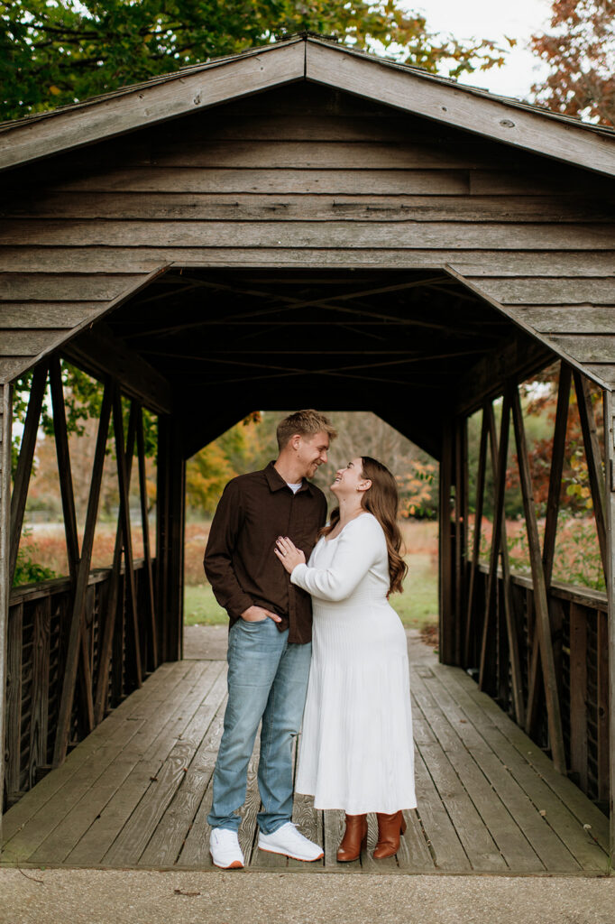Couple posing under a covered bridge during their South Bend engagement photos at St. Patrick’s County Park.