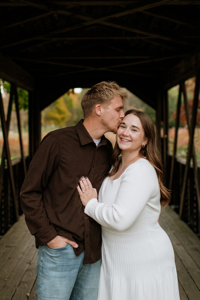 Man kissing his fiancé on the cheek.