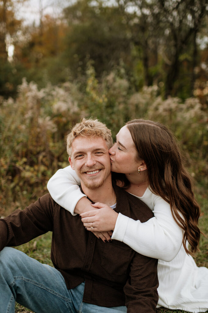 Close up photo of a woman kissing her fiancés cheek during their South Bend engagement photos at St. Patrick’s County Park.