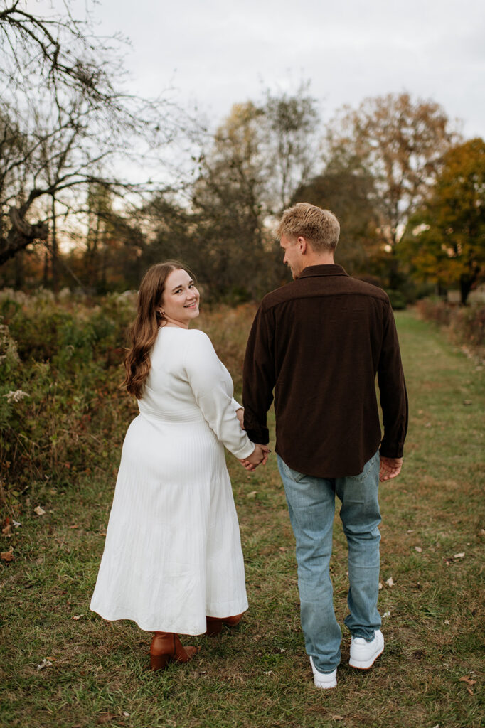 Woman looking back at the camera as she and her fiancé walk away during their photoshoot.