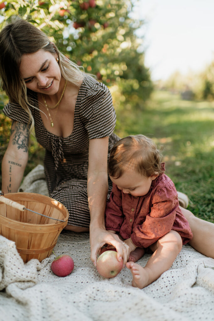 Mother and baby playing with apples during a. during apple orchard family photos at Garwood Orchards. 