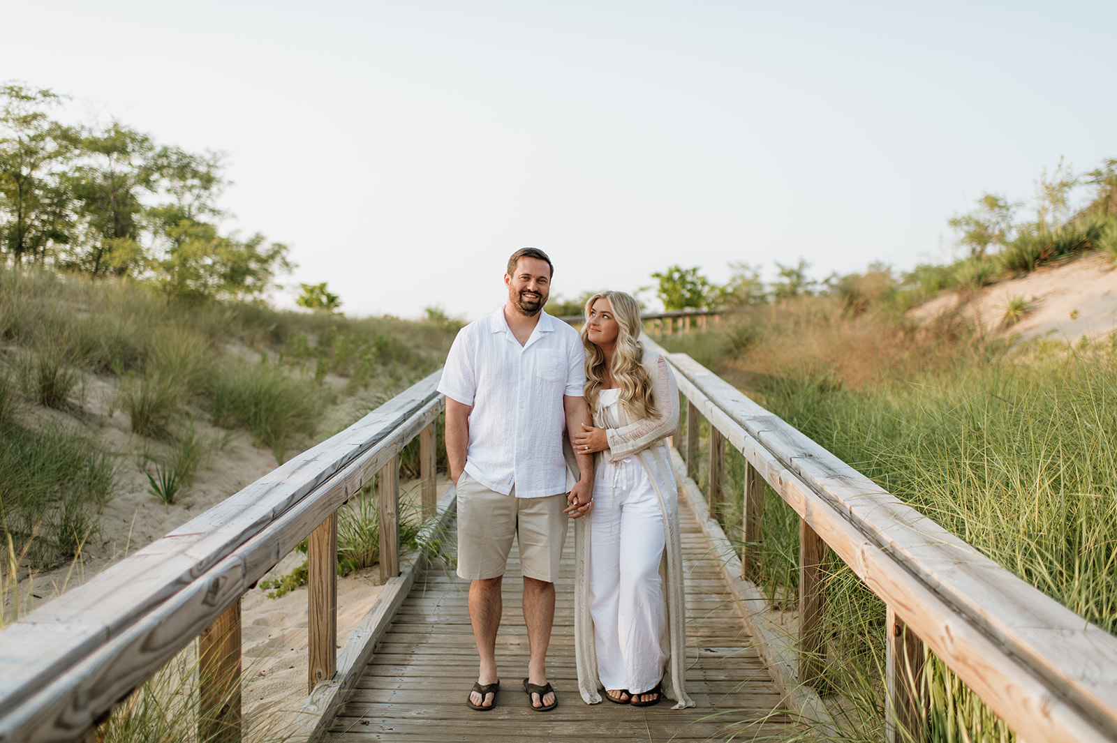 Couple standing om a boardwalk for their engagement photos at New Buffalo Beach - a Northern Indiana Photo Location.