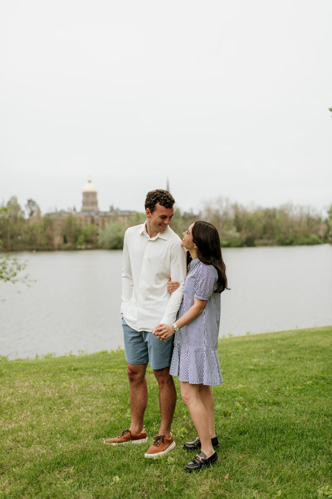 Couple holding hands near the water after their surprise proposal at University of Notre Dame - a Northern Indiana Photo Location.
