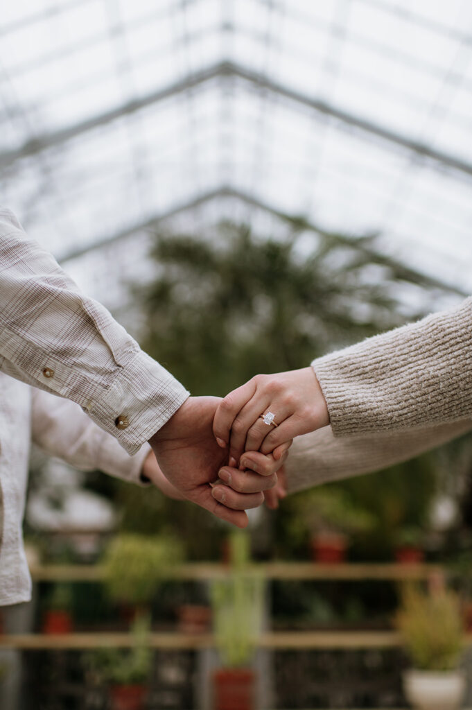 Couple holding hands for engagement photos inside of Potawatomi Conservatory.