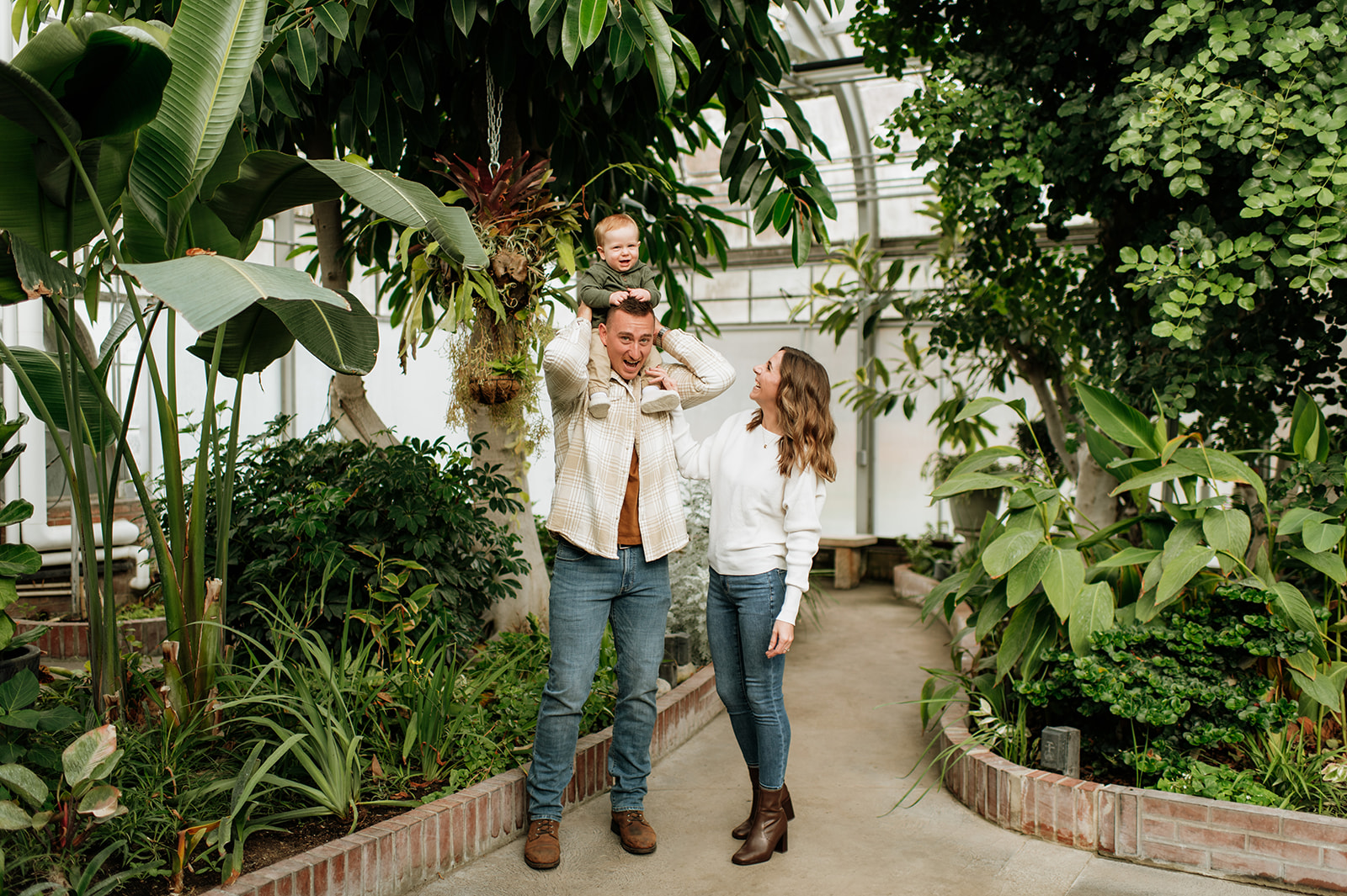 Family of three posing for family photos inside of Potawatomi Conservatory in South Bend, Indiana.