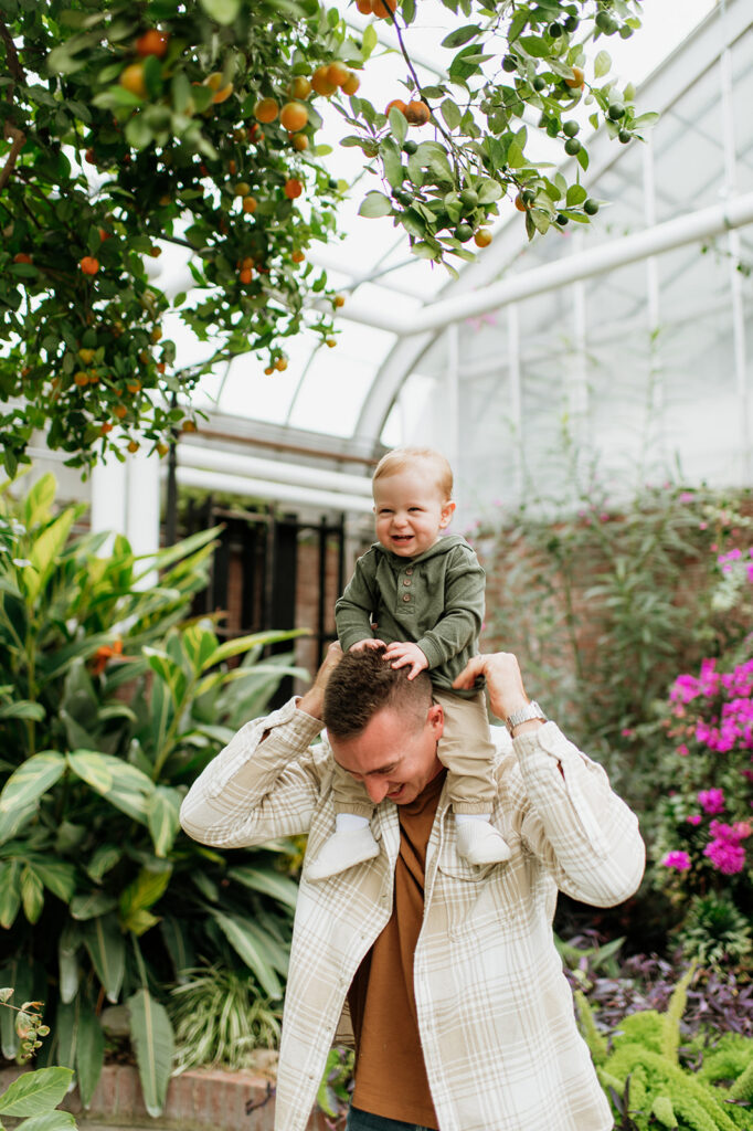 Father holding his baby on his shoulder for family photos inside of Potawatomi Conservatory in South Bend.