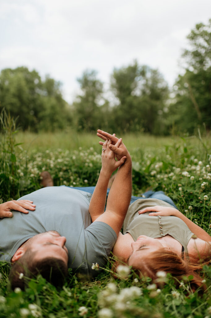 Couple lying in the grass during a relaxed Northern Indiana engagement session on private property.