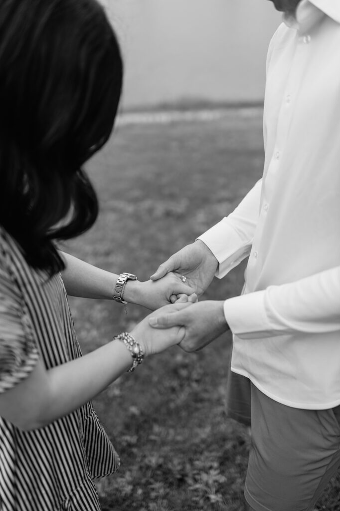 Black and white close up shot of a couple holding hands.