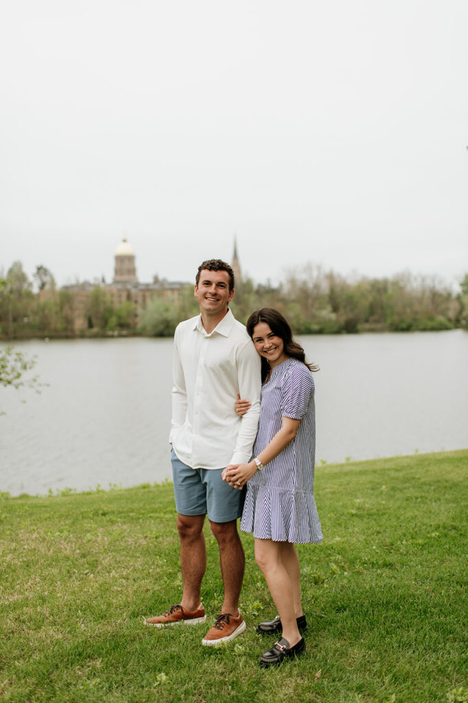 Man and woman posing in front of Saint Joseph’s Lake after their Notre Dame proposal.