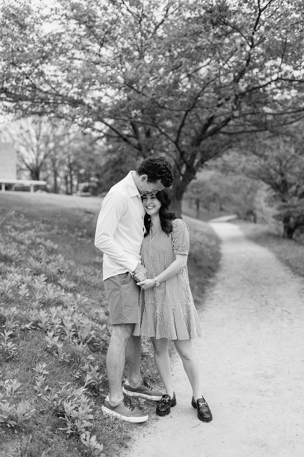Black and white candid photo of a couple hugging each other along the paths at Notre Dame.