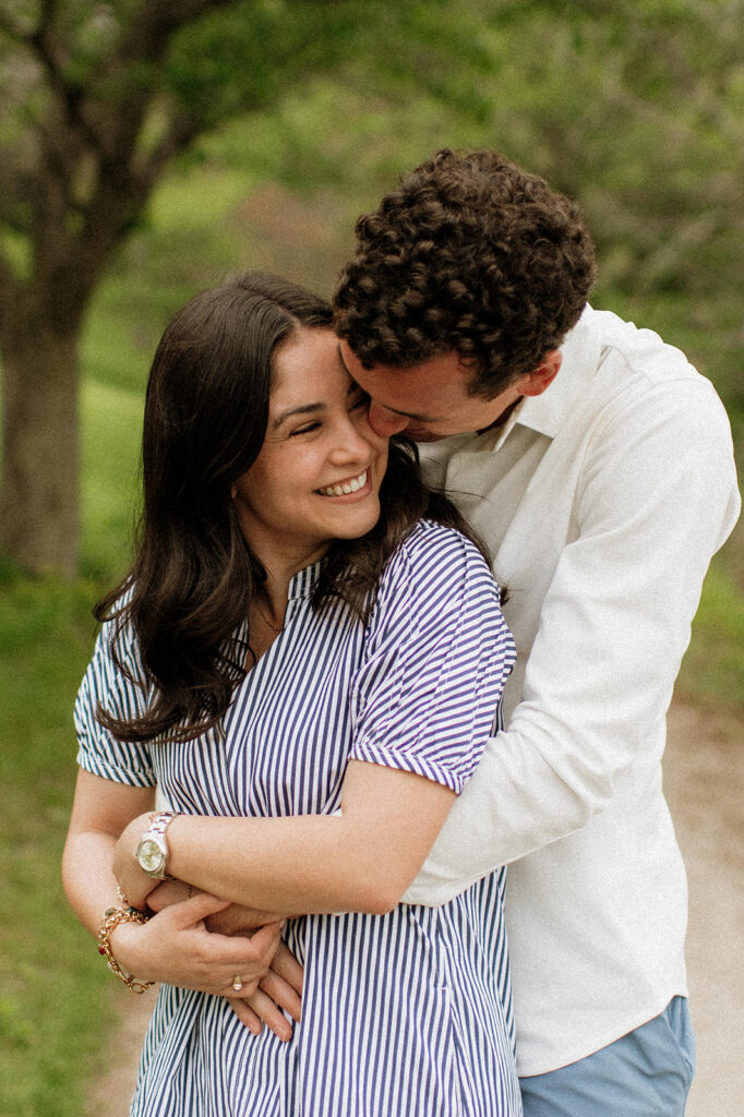 Man hugging his fiancé from behind while smiling.