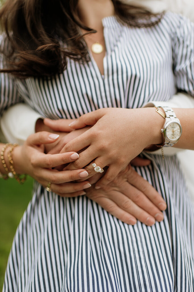 Close up shot of a man hugging his fiancé around her waist.