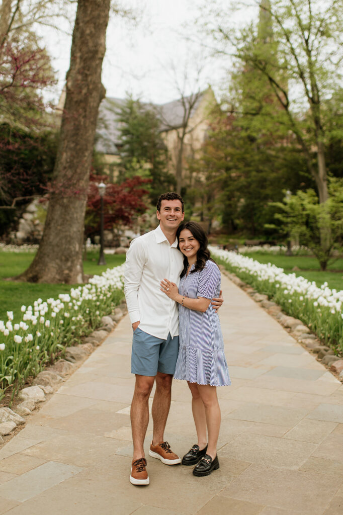Man and woman posing on the pathway near the Grotto surrounded by white tulips.
