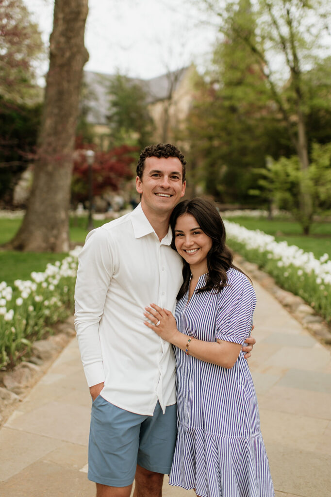 Man and woman posing on the pathway near the Grotto surrounded by white tulips.