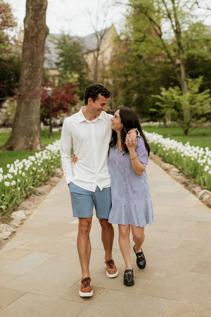 Man and woman walking the pathway near the Grotto surrounded by white tulips.