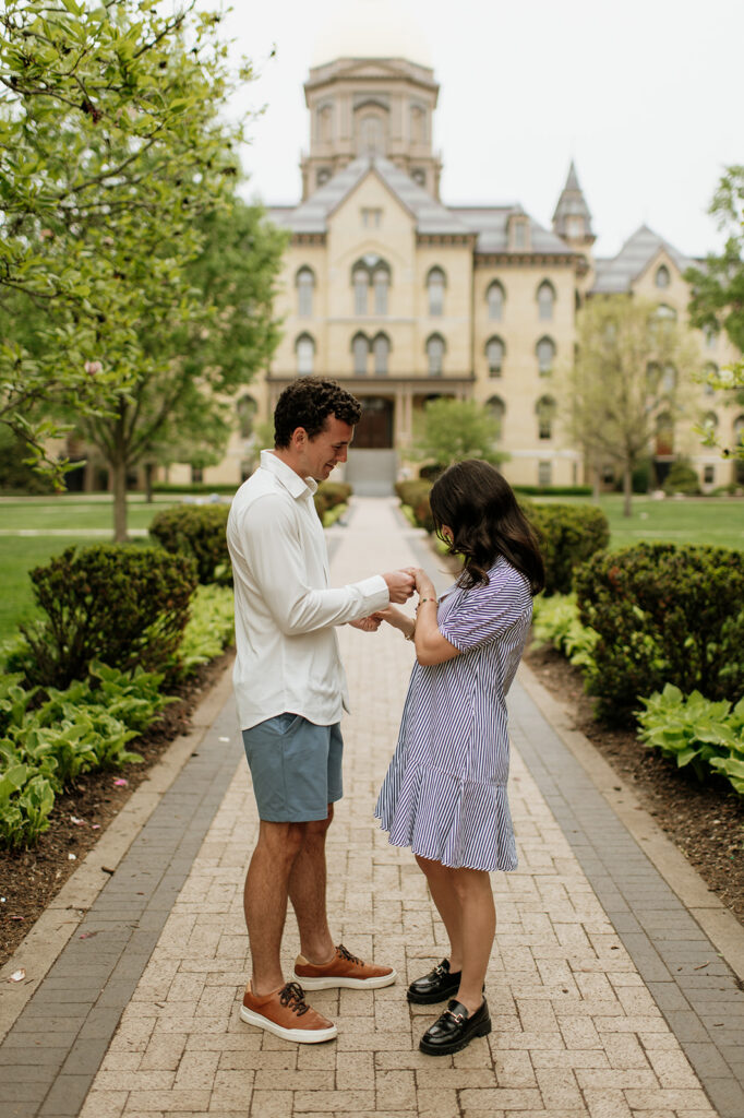 Woman admiring her engagement ring in front of the main building and Golden Dome for their Notre Dame proposal photos.