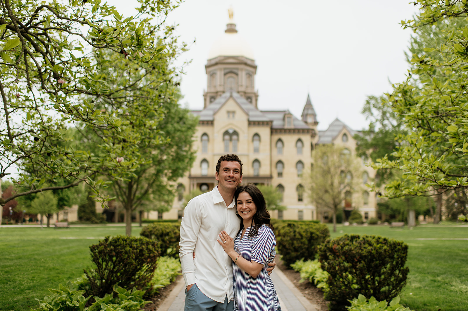 Man and woman posing in front of the main building and Golden Dome for their Notre Dame proposal photos.