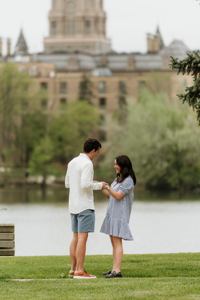 Man holding his soon to be fiancées hand in front of Saint Joseph's Lake at The University of Notre Dame.